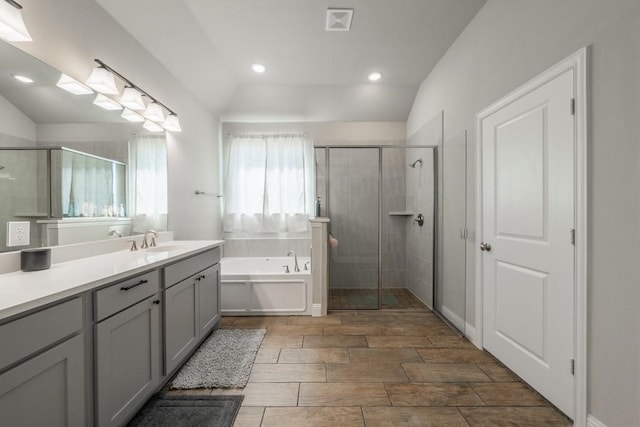 bathroom with vanity, shower with separate bathtub, and vaulted ceiling