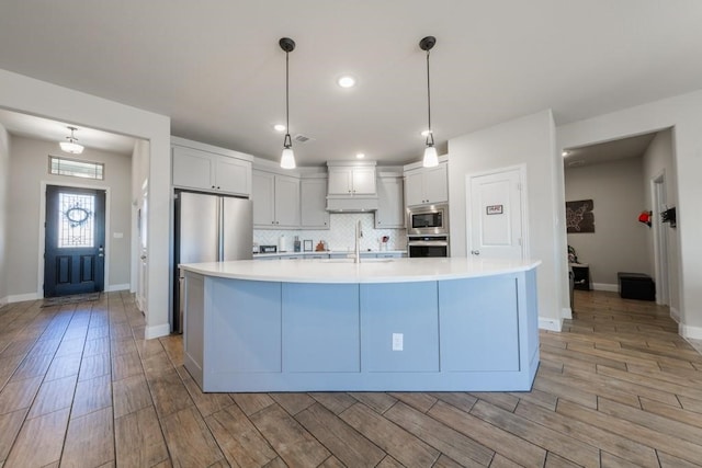 kitchen featuring appliances with stainless steel finishes, decorative light fixtures, light hardwood / wood-style flooring, and white cabinetry