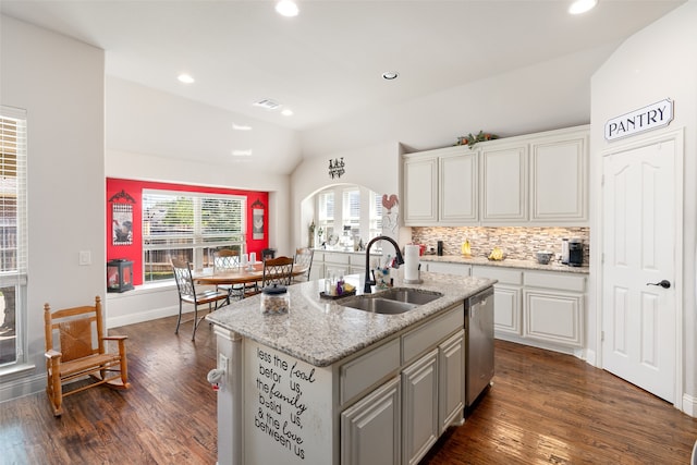 kitchen featuring an island with sink, sink, dark wood-type flooring, dishwasher, and vaulted ceiling