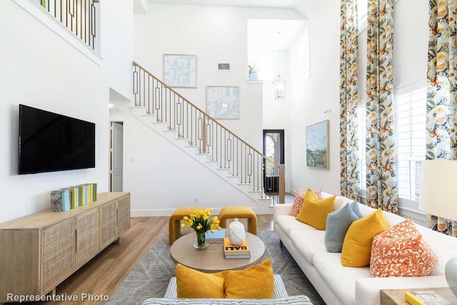 living room with a towering ceiling, hardwood / wood-style floors, and a wealth of natural light