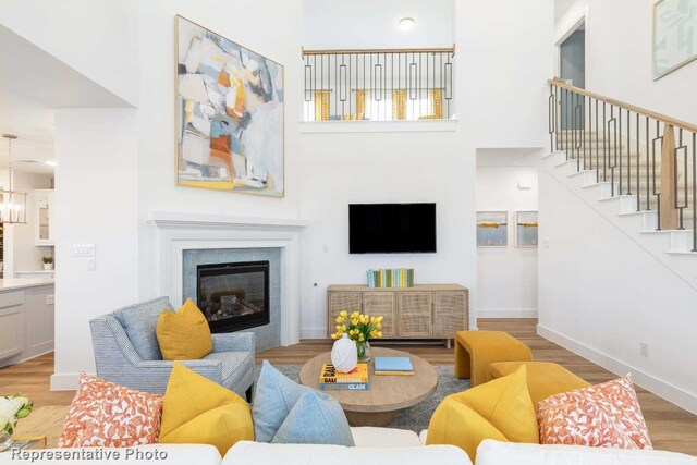 living room featuring a fireplace, a high ceiling, an inviting chandelier, and light wood-type flooring