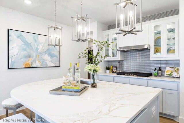 kitchen with wood-type flooring, white cabinets, black gas cooktop, and decorative light fixtures