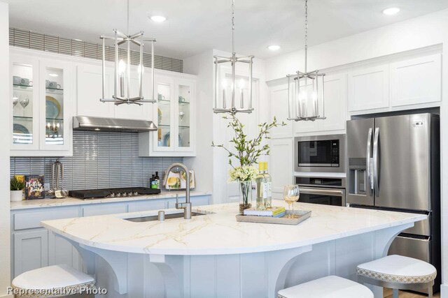 kitchen featuring a center island with sink, decorative light fixtures, appliances with stainless steel finishes, and white cabinets