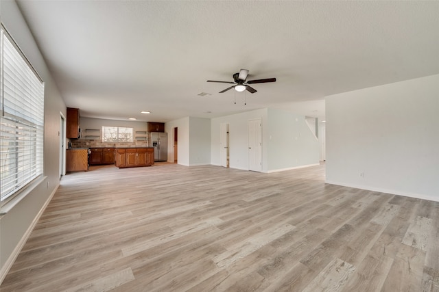 unfurnished living room featuring ceiling fan and light hardwood / wood-style flooring