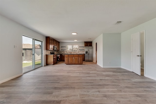 kitchen with decorative backsplash, appliances with stainless steel finishes, and light hardwood / wood-style flooring