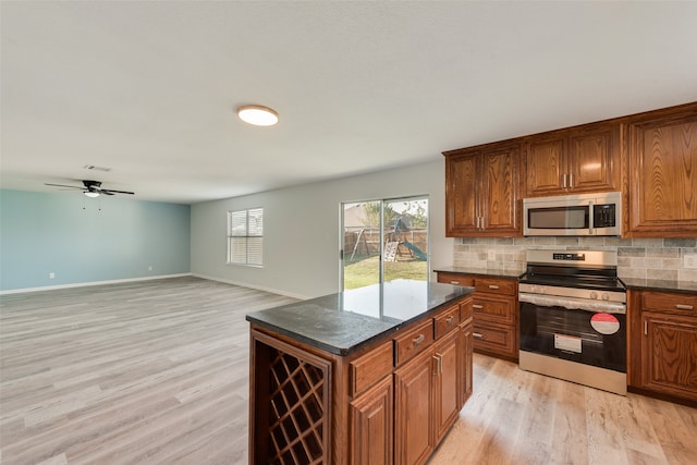 kitchen with a kitchen island, ceiling fan, decorative backsplash, stainless steel appliances, and light hardwood / wood-style floors