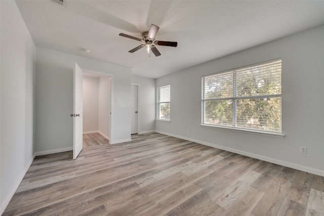 unfurnished bedroom featuring light wood-type flooring, multiple windows, and ceiling fan