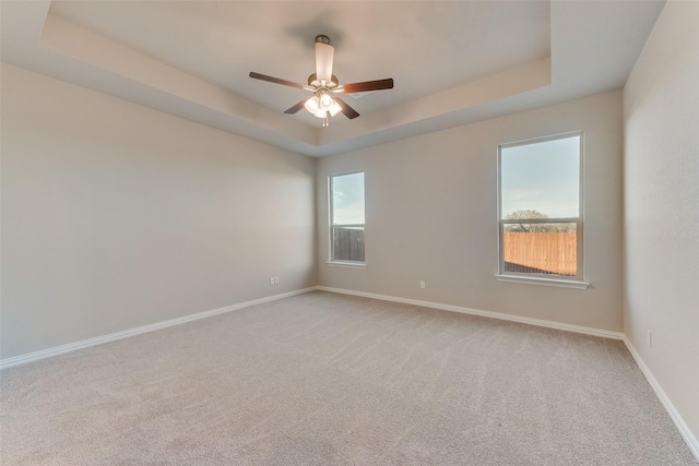 carpeted spare room featuring ceiling fan and a raised ceiling