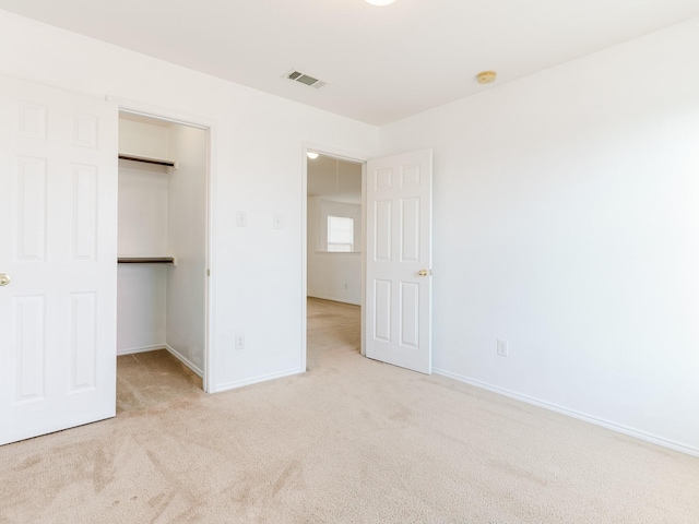 unfurnished bedroom featuring light carpet, baseboards, visible vents, and a spacious closet