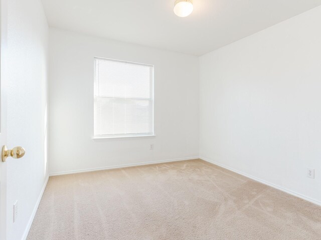 empty room with baseboards and light colored carpet