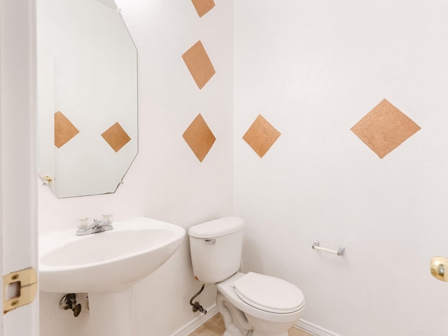 bathroom featuring toilet, baseboards, and a sink