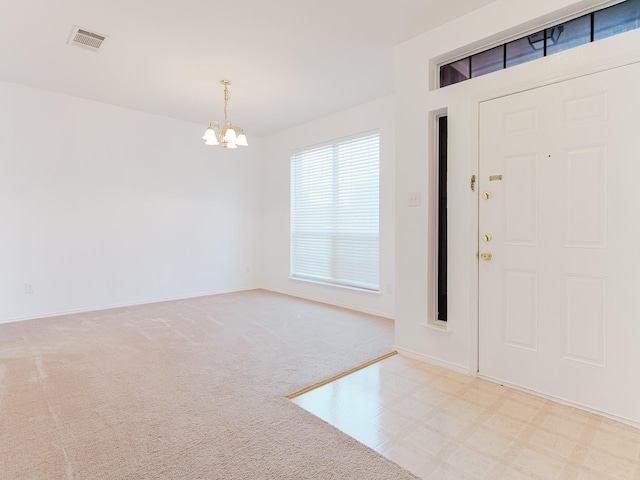 carpeted entrance foyer featuring visible vents, baseboards, and an inviting chandelier