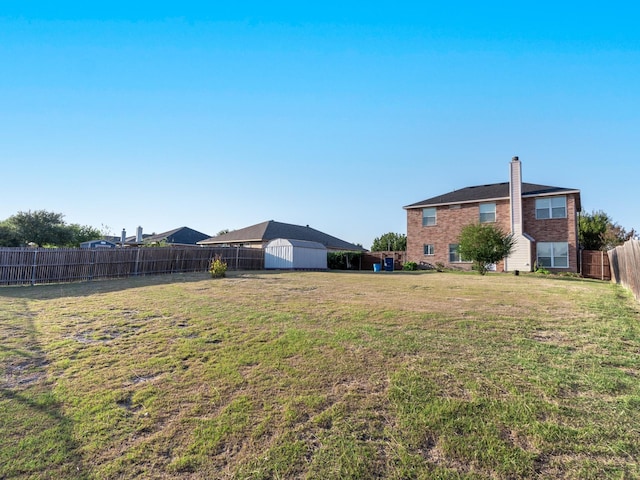 view of yard featuring a storage shed, an outbuilding, and a fenced backyard