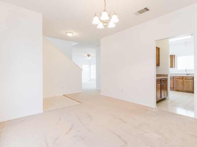 empty room with visible vents, baseboards, a sink, ceiling fan with notable chandelier, and light carpet