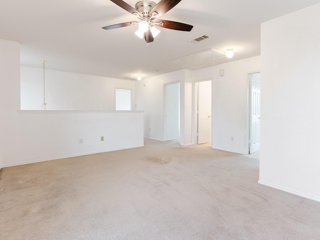 spare room featuring attic access, light carpet, baseboards, visible vents, and ceiling fan