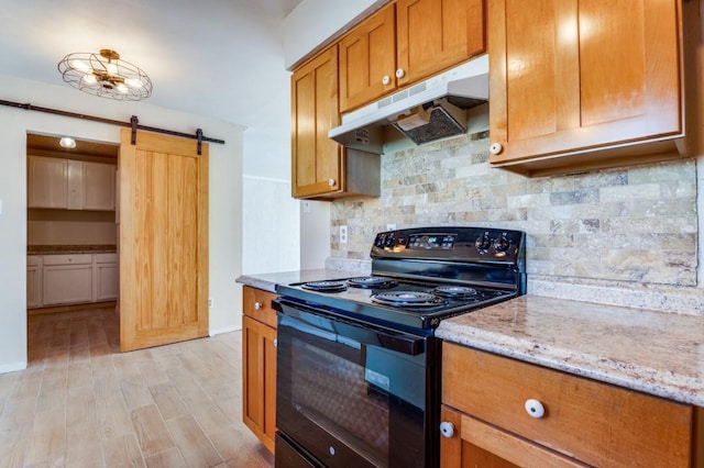 kitchen with light stone countertops, black / electric stove, backsplash, light hardwood / wood-style flooring, and a barn door