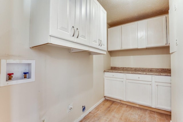 clothes washing area with cabinets, a textured ceiling, hookup for a washing machine, and hookup for an electric dryer