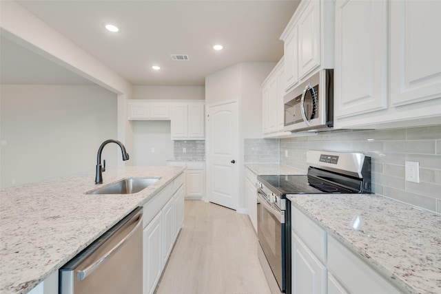 kitchen featuring sink, light stone counters, stainless steel appliances, and white cabinetry