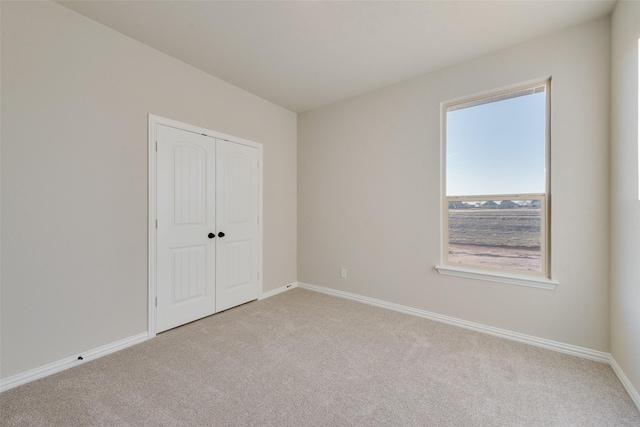 unfurnished bedroom with light colored carpet and a closet