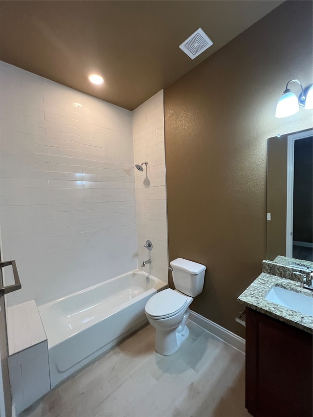 full bathroom featuring tiled shower / bath, vanity, and toilet