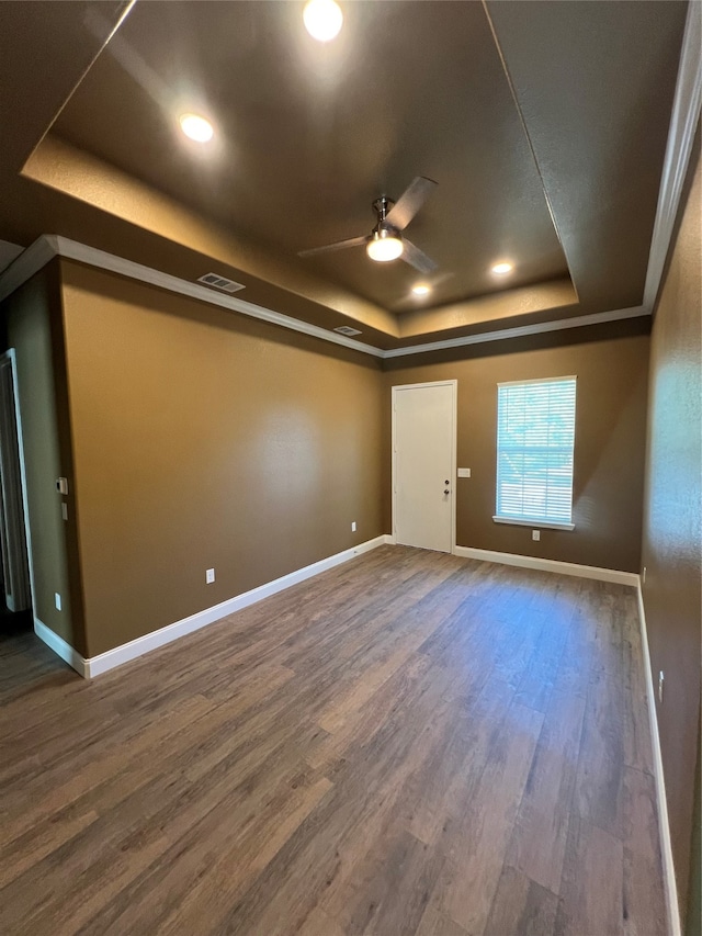 empty room featuring ceiling fan, a tray ceiling, and dark hardwood / wood-style floors