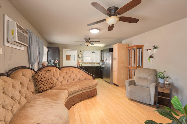 living room with an AC wall unit, sink, and light hardwood / wood-style floors