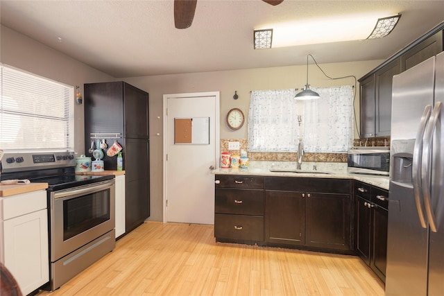 kitchen featuring pendant lighting, sink, ceiling fan, appliances with stainless steel finishes, and light wood-type flooring