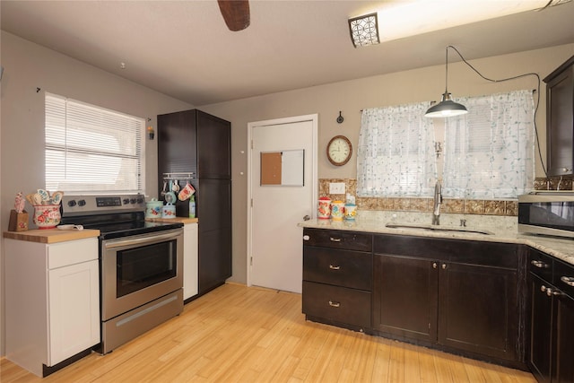 kitchen with sink, stainless steel appliances, white cabinets, decorative light fixtures, and light wood-type flooring