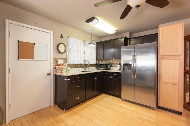 kitchen featuring decorative light fixtures, sink, decorative backsplash, stainless steel appliances, and light hardwood / wood-style flooring