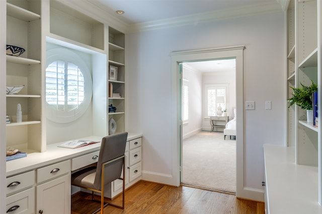 office area featuring crown molding, light wood-type flooring, and built in desk