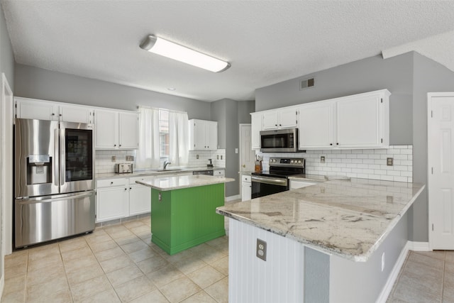 kitchen featuring appliances with stainless steel finishes, a center island, white cabinetry, and light stone counters