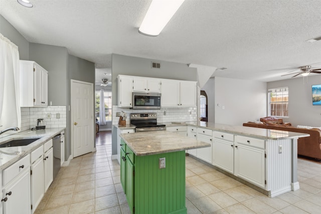 kitchen featuring a center island, appliances with stainless steel finishes, white cabinetry, and a healthy amount of sunlight