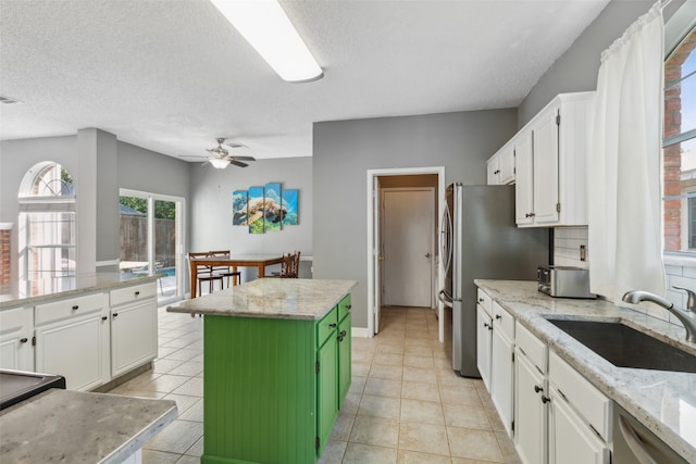 kitchen featuring white cabinets, light stone counters, a kitchen island, stainless steel appliances, and sink