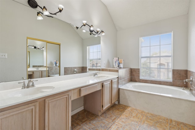 bathroom with vanity, lofted ceiling, and a washtub