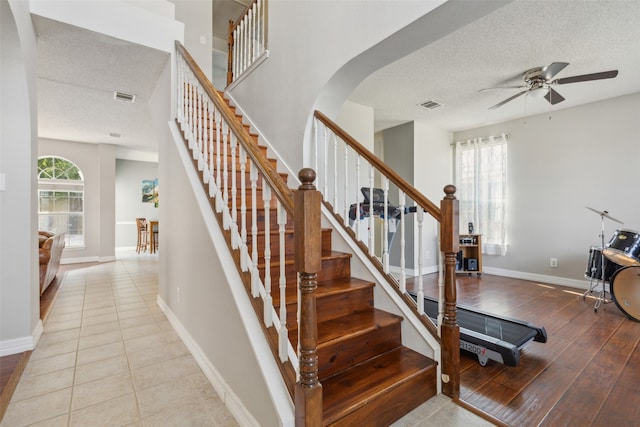 stairs with a textured ceiling, hardwood / wood-style floors, and ceiling fan