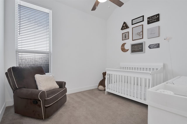 carpeted bedroom with ceiling fan, lofted ceiling, and a crib