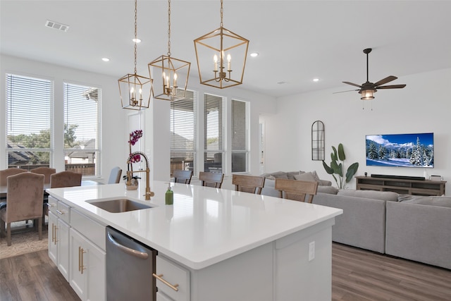 kitchen with dark wood-type flooring, dishwasher, sink, and a kitchen island with sink