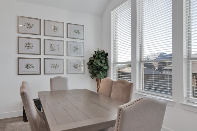 dining room with wood-type flooring and vaulted ceiling