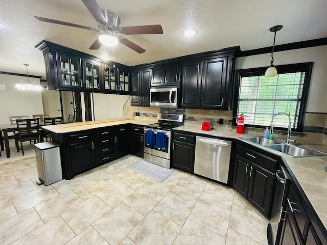 kitchen featuring sink, decorative backsplash, hanging light fixtures, appliances with stainless steel finishes, and ornamental molding