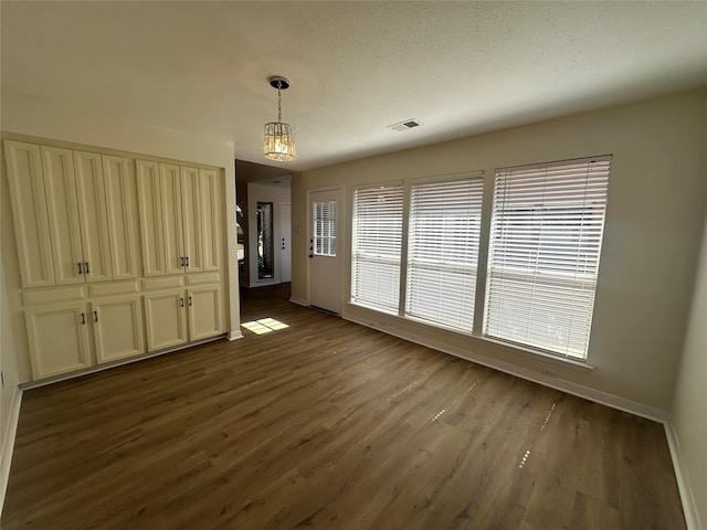 unfurnished dining area featuring dark wood-type flooring and a wealth of natural light