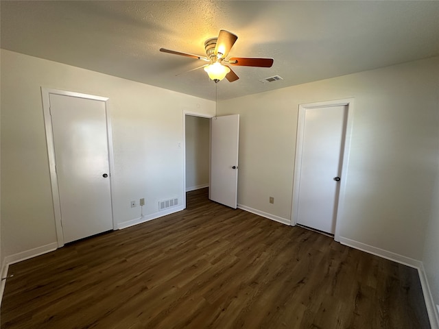 unfurnished bedroom with ceiling fan and dark wood-type flooring