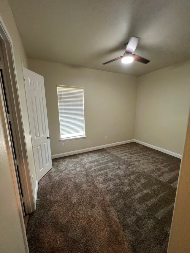 unfurnished room featuring dark colored carpet and ceiling fan