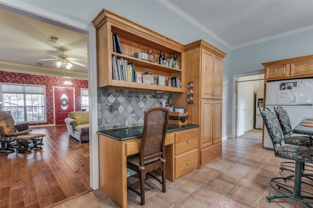 office with crown molding, built in desk, ceiling fan, and light hardwood / wood-style floors