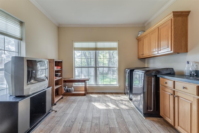 washroom featuring separate washer and dryer, crown molding, light hardwood / wood-style floors, and cabinets