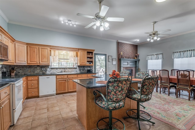 kitchen with sink, crown molding, white appliances, backsplash, and a center island