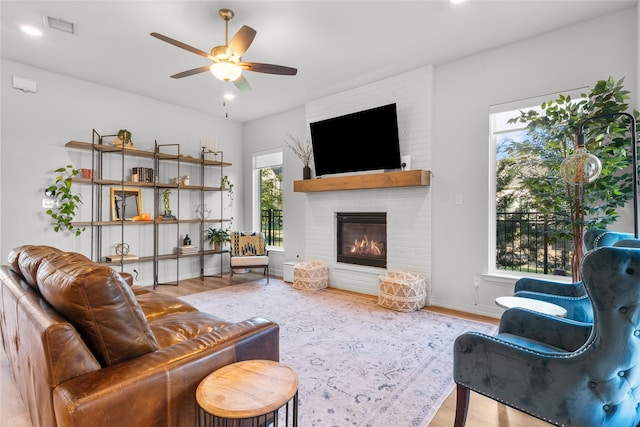 living room featuring a fireplace, hardwood / wood-style floors, and ceiling fan