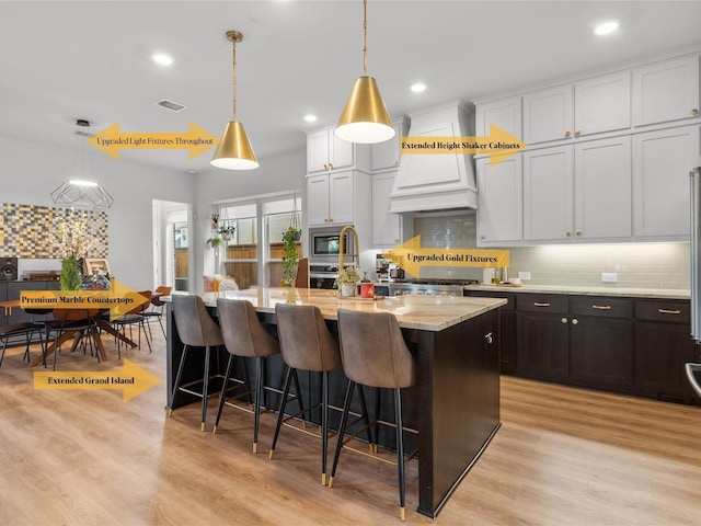 kitchen with a center island with sink, visible vents, backsplash, and stainless steel appliances