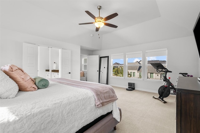 carpeted bedroom with a raised ceiling, vaulted ceiling, and ceiling fan