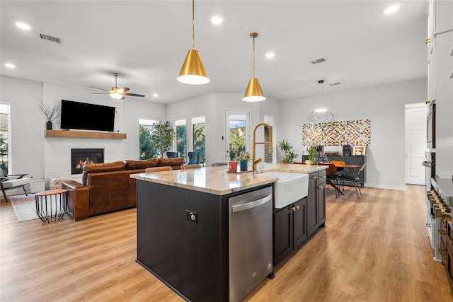 kitchen featuring a fireplace, visible vents, a sink, and stainless steel dishwasher