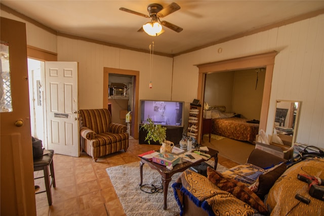 living room with ornamental molding, ceiling fan, and wood walls